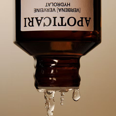 A few drops of verbena hydrosol pouring from an amber Apoticari bottle