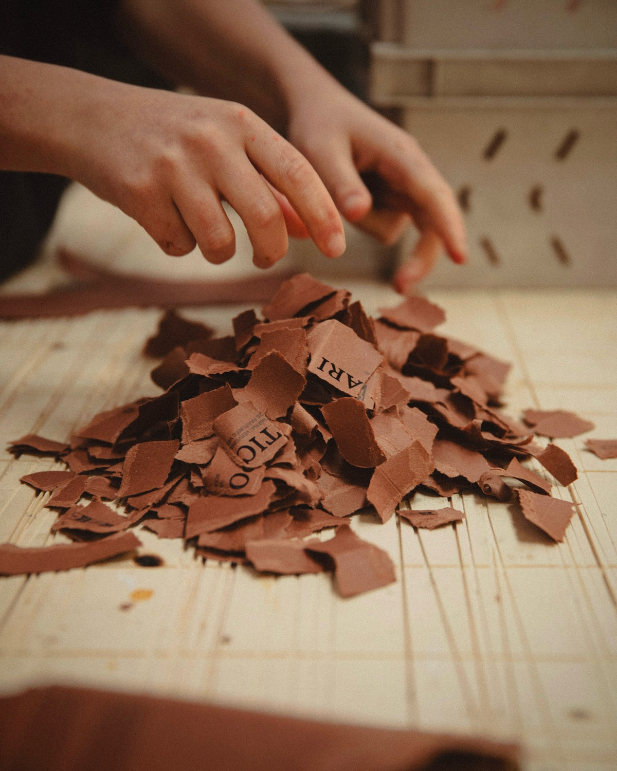 Hands tearing Apoticari boxes into small pieces of cardboard.